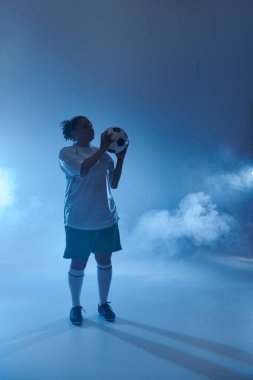 Dişi bir futbolcu oynamaya hazır, elinde bir kararlılıkla topu tutuyor..