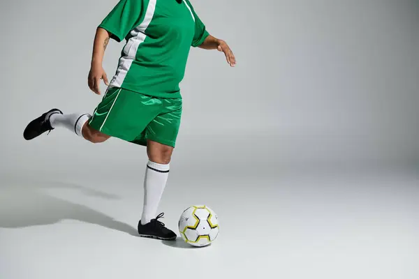 A woman in a green soccer uniform dribbles a ball with her right foot.