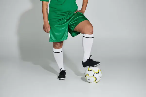 stock image A woman in a green soccer jersey and shorts posing with a soccer ball.