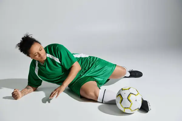 Female soccer player rests  green attire stark against white.