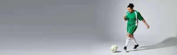 A female athlete in a green jersey dribbles a soccer ball on a white studio background.