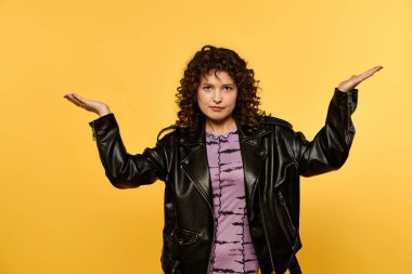 A young woman with curly hair poses in a black leather jacket against a vibrant yellow background. clipart