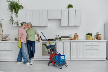 Modern bir mutfakta lezbiyen bir çift, sevgi dolu bir ilişki ve ortak sorumluluklar gösteriyorlar..