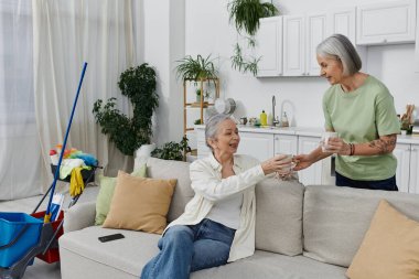 Lezbiyen bir çift, modern dairelerini temizledikten sonra bir fincan kahvenin tadını çıkarıyor..