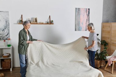Gündelik giyinmiş iki olgun lezbiyen kadın modern dairelerinde birlikte yatıyorlar..