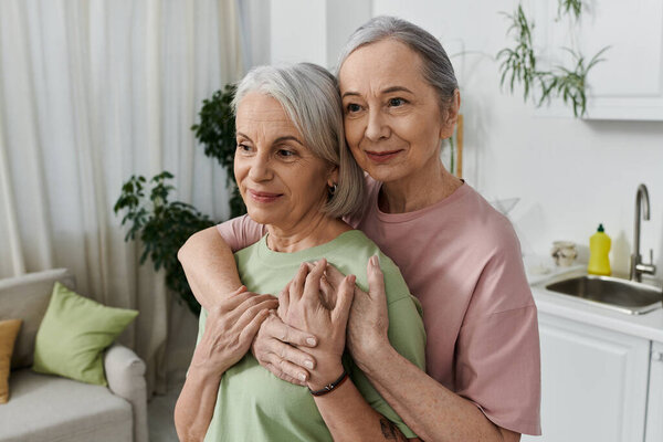 A mature lesbian couple embraces in their modern apartment, showcasing love and domesticity.