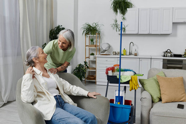 Две зрелые лесбиянки расслабляются после уборки своей современной квартиры, наслаждаясь минутой покоя.