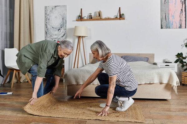 Две зрелые лесбиянки вместе убирают свою современную квартиру.