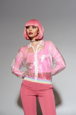 Pembe saçlı ve canlı kıyafetli bir kadın fotoğraf için poz veriyor..