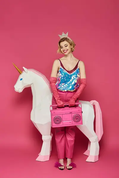 stock image A woman dressed in pink and a sparkly top poses with a unicorn cutout and a pink boombox.