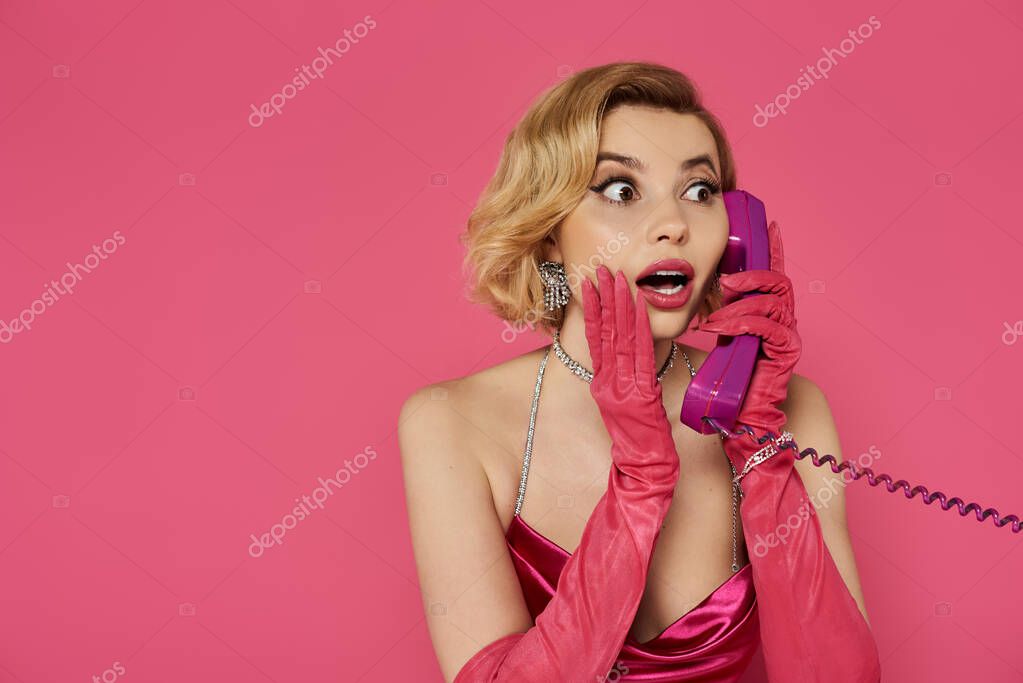 A woman in a pink dress and gloves holds a purple phone to her ear, looking shocked and surprised.