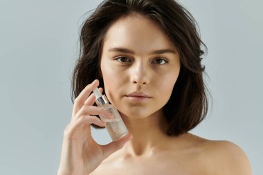 Renkli bir arkaplan önünde bir kadın yüzüne serum uyguluyor..