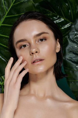 Kısa siyah saçlı bir kadının yakın plan portresi, canlı yeşil bir fona karşı poz veriyor..