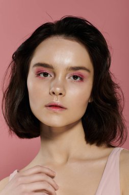 Pembe göz farı olan bir kadının portresi, pembe bir arka fona karşı..