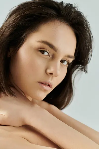 stock image A young woman with brown hair poses, looking directly at the camera.