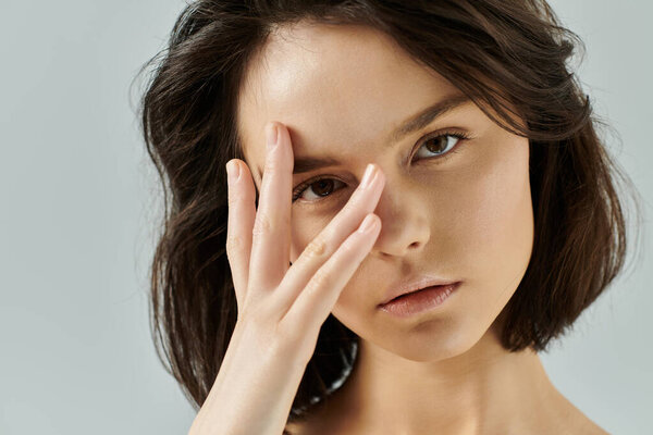 Портрет крупным планом женщины с частично закрывающей лицо рукой.