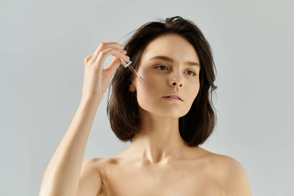 Молодая женщина наносит сыворотку на лицо капельницей.