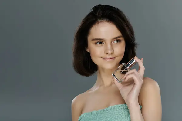 stock image A woman holds a bottle of perfume and smiles.