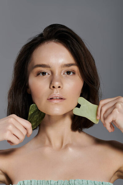 A woman uses a jade gua sha for a facial massage.