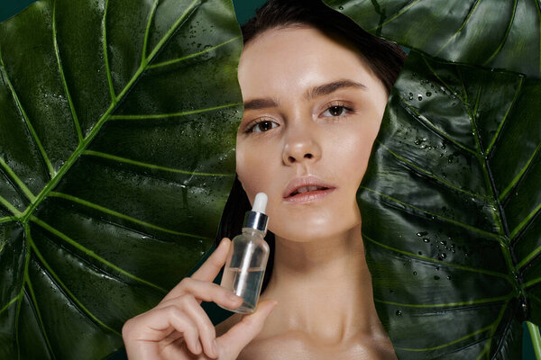 A young woman poses with a serum bottle, her face framed by vibrant, dewy leaves.