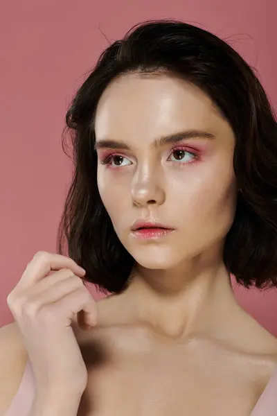 stock image Woman with short dark hair against pink backdrop, softly illuminated.