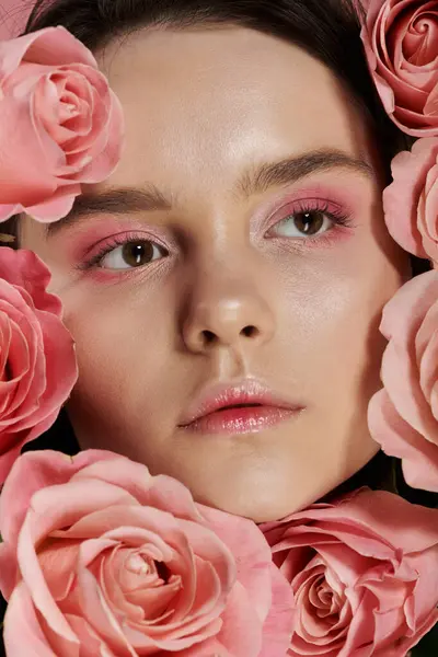 stock image A close-up portrait of a womans face surrounded by pink roses.