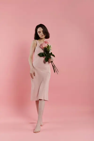 stock image A woman walks in pink holding pink roses against a pink backdrop.