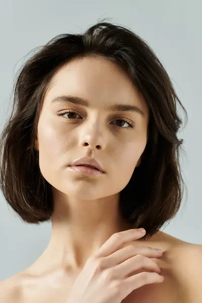 stock image A woman with dark hair looks directly at the camera, her hand resting on her shoulder.