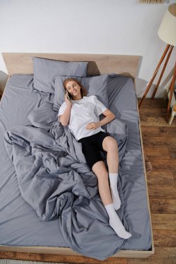 Genç bir kadın telefonda konuşurken gülümsüyor..