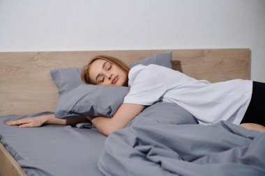 Genç bir kadın evinde sakin bir anın tadını çıkararak yatağında huzur içinde dinleniyor..