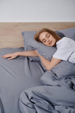 Genç bir kadın evinde sakin bir anın tadını çıkararak yatağında huzur içinde dinleniyor..