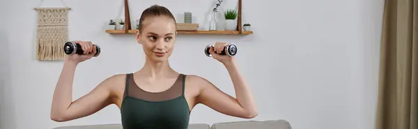 stock image A young woman lifts dumbbells during a home workout.
