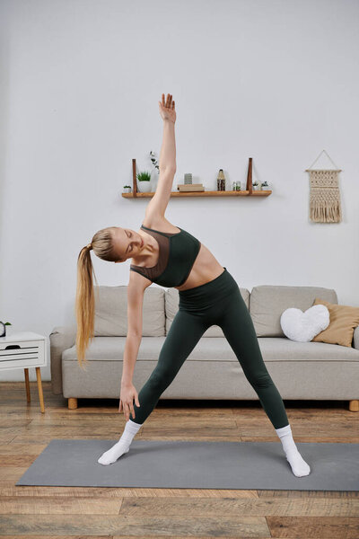 A young woman stretches on a yoga mat in her living room.