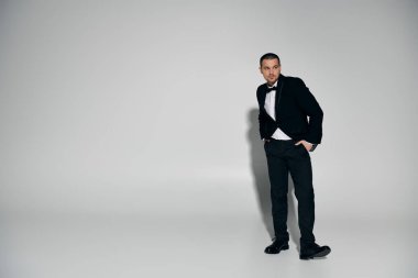 A man in a tuxedo stands confidently in front of a plain white background. clipart