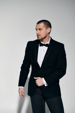 A man in a tuxedo stands confidently, his gaze directed off-camera. clipart