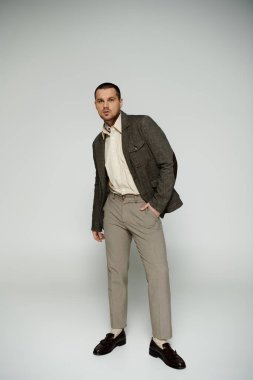 Gri ceketli ve kahverengi pantolonlu şık bir adam..
