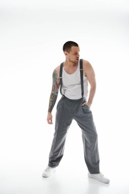 A man in grey trousers and suspenders poses against a white background. clipart