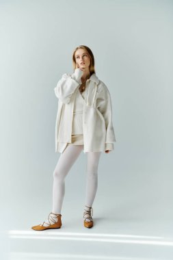 Beyaz giysili genç bir kadın, düşünceli, yumuşak ışıkla yıkanmış..