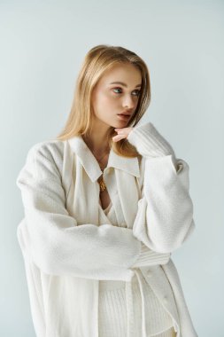 A young woman dressed in a white sweater looks away from the camera, lost in thought. clipart