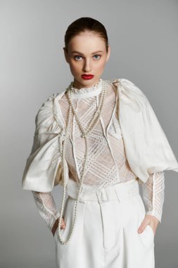 A young woman poses in a white lace top with pearl necklaces and a matching white pantsuit. clipart