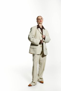 A stylish young woman stands confidently in a cream suit, her eyes looking directly at the camera. clipart