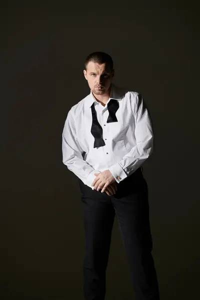 stock image Man in white shirt, black bow tie, focused gaze against dark background.