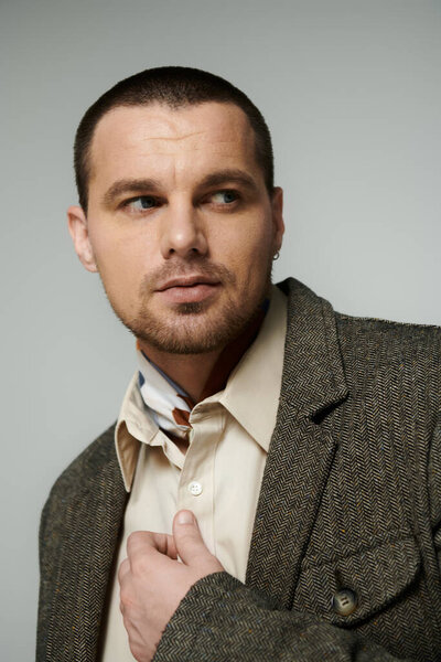 A stylish man poses in a studio, adjusting his jacket.