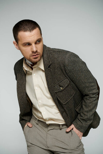 A stylish man with a crisp white shirt and a textured jacket poses confidently in a studio setting.