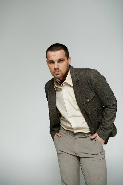 A stylish man poses in a studio setting, with a relaxed yet confident stance.