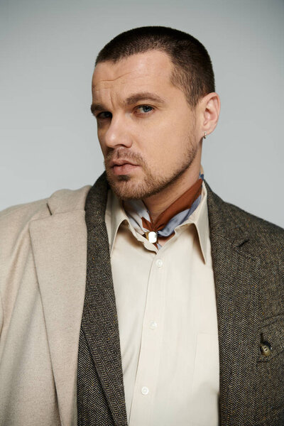 Short-haired man in white shirt, brown tie, beige jacket.