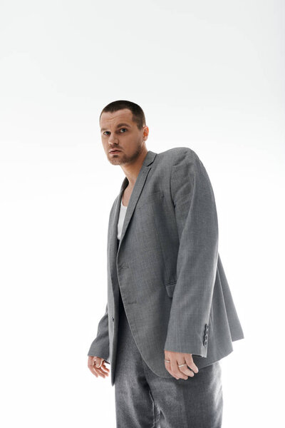 A man in a gray suit stands confidently, looking directly at the camera.