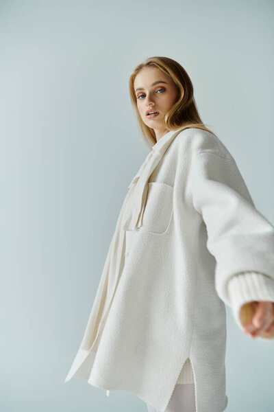 Женщина в белом халате смотрит через плечо на камеру.