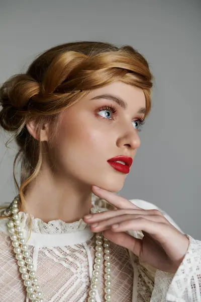 stock image A young woman with red lipstick and a pearl necklace gazes thoughtfully into the distance.