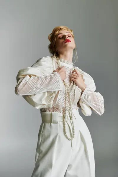 stock image Young woman in white blouse and pants gazes up with eyes closed, wearing pearls.